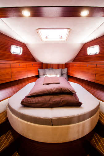 Schlafkabine in rotem Holz, Leder und Fenstern auf dem Hausboot Nautiner