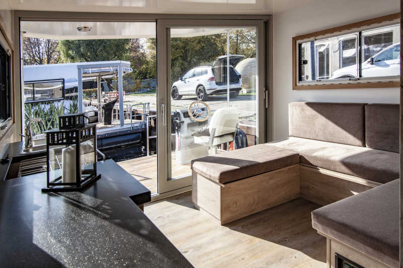 Sonniges Wohnzimmer mit Terrasse und Holzboden auf dem Hausboot Flexmobil