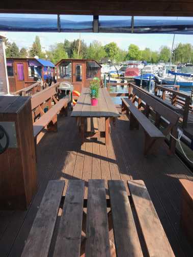 Outdoor area with table and benches on a wooden raft with grill on board