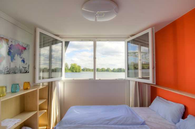 Bedroom with two beds and water view on the houseboat Loreen