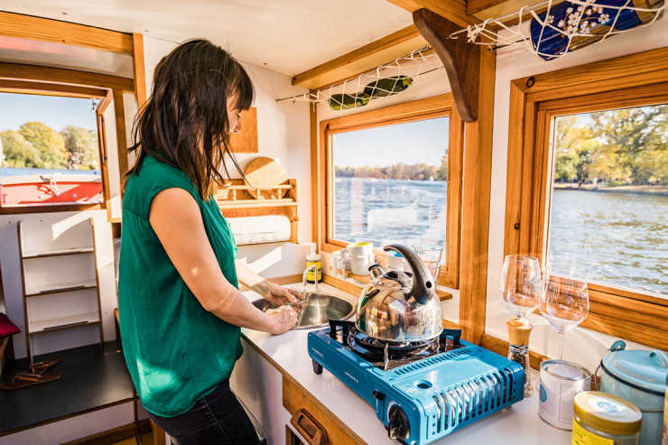 A woman cooks in the kitchen of the houseboat Wasserkutsche