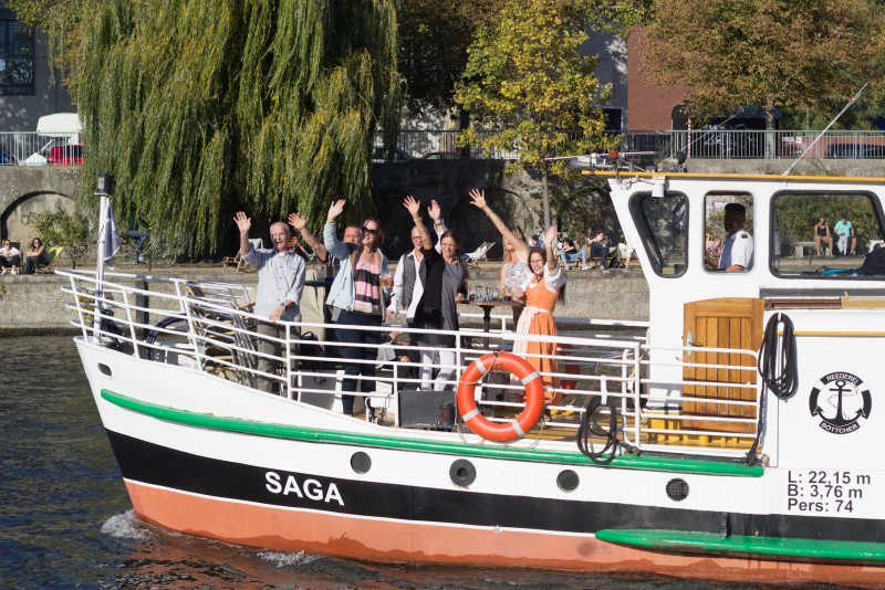 Foredeck of the party boat Saga with waving guests on a boat tour through the Landwehr Canal
