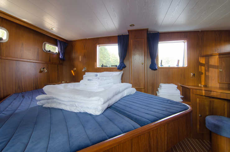 Aft cabin of the Carlotta houseboat with large bed and windows