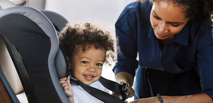 Mamá con su guagua poniéndole silla de bebé para auto.