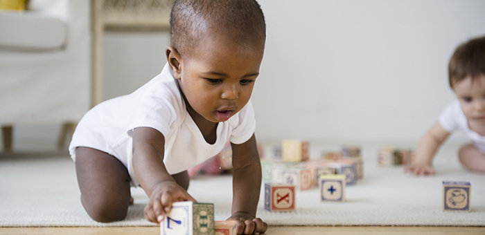 D-Toddler_wearing_a_babygro_playing_with_wooden_blocks