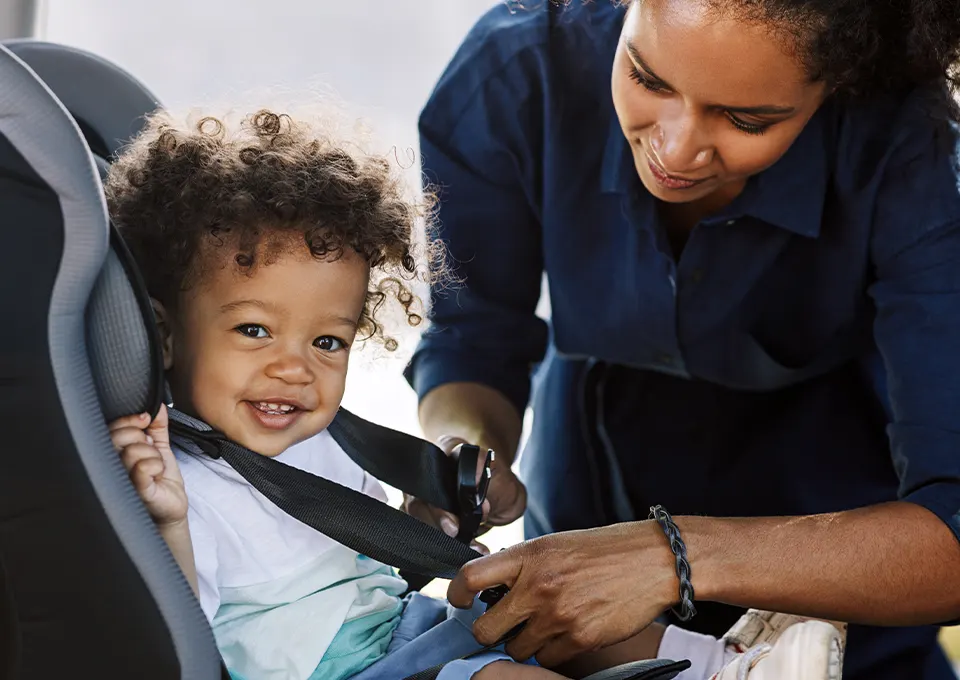 Mamá con su guagua poniéndole silla de bebé para auto.