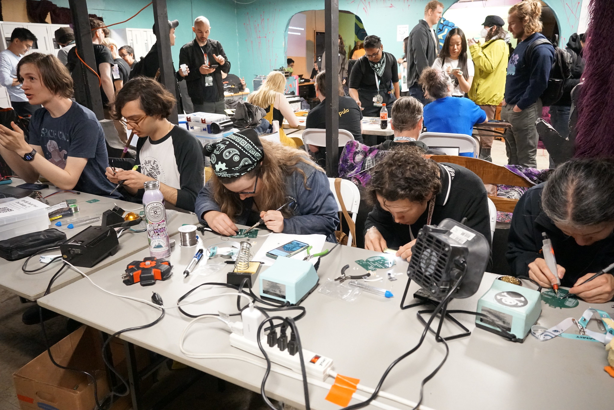 Participants at the Open Hardware Summit 2024 at a table soldering.