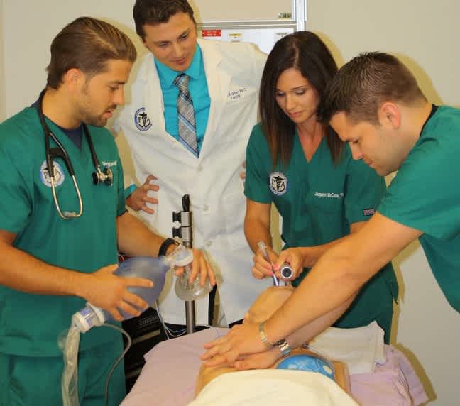 Photograph of PA students with Sean Kramer, Director of the PA Program working on a fake patient