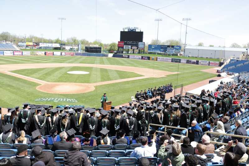 Students stand during commencement at Classic Park