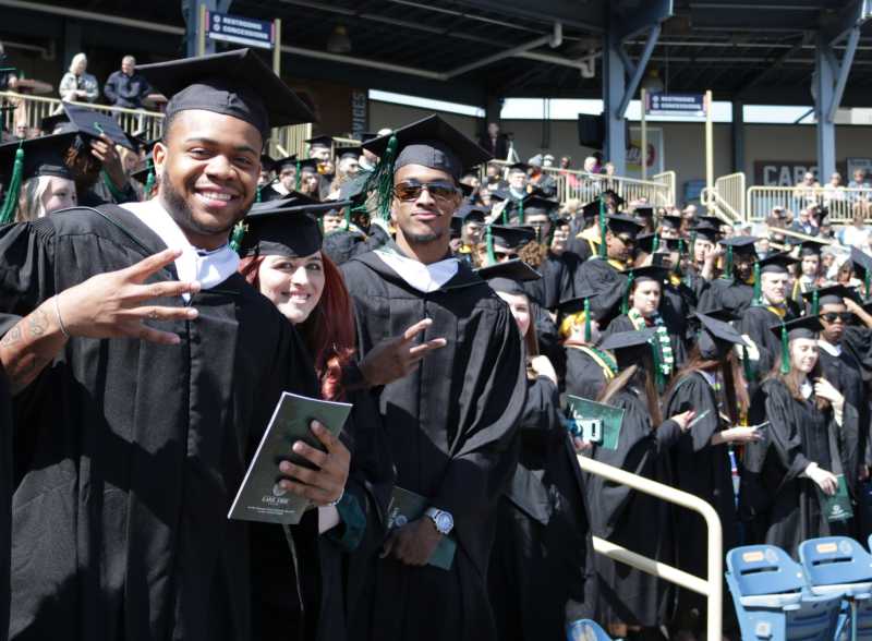Students smile for a photo while waiting for their names to be called at commencement 