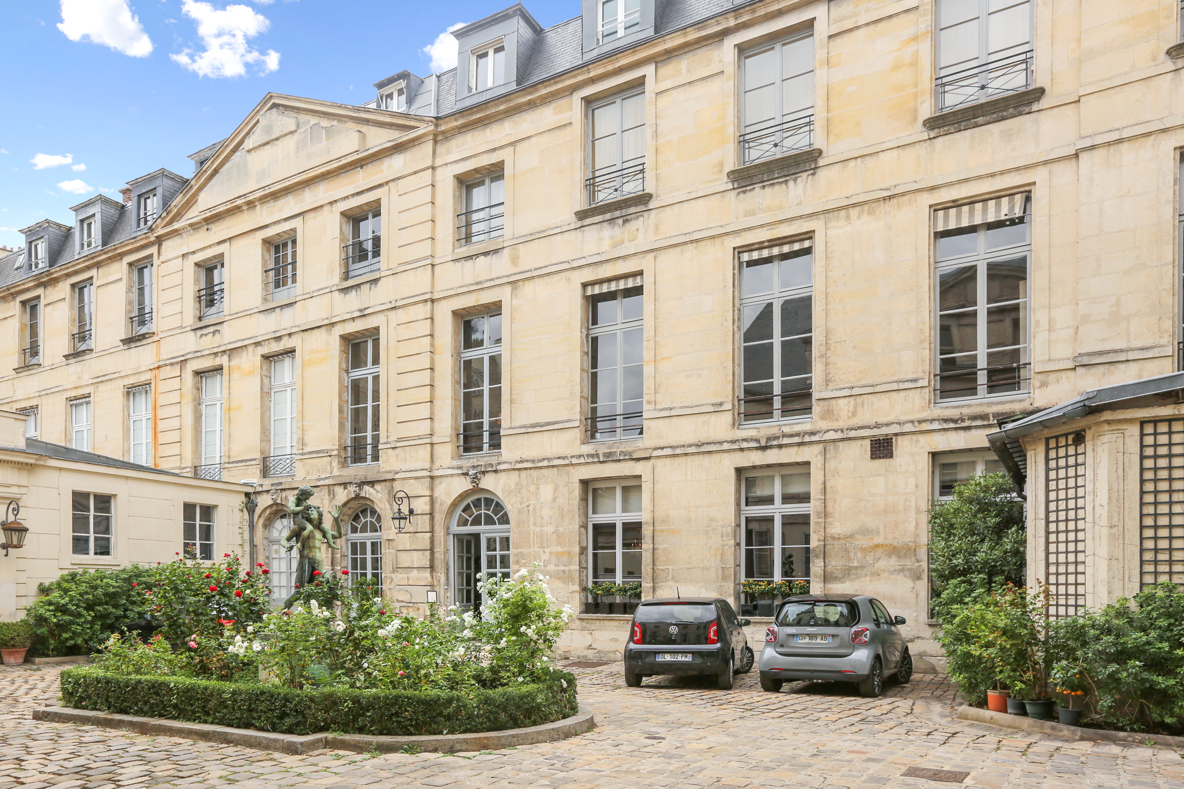 Exterior of apartment with French doors and greenery in courtyard.