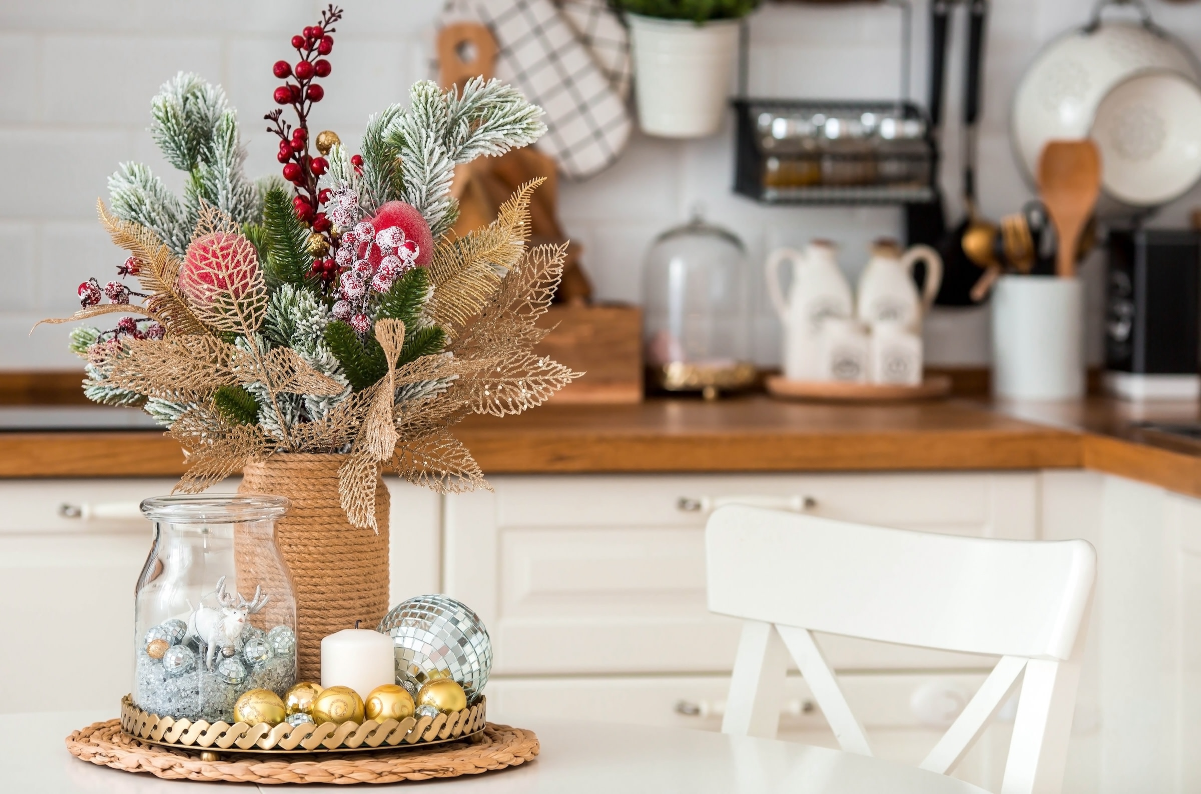A spruce bouquet with red berries on a white kitchen table. Christmas decorations in the interior. The concept of preparing for the New year holiday.
