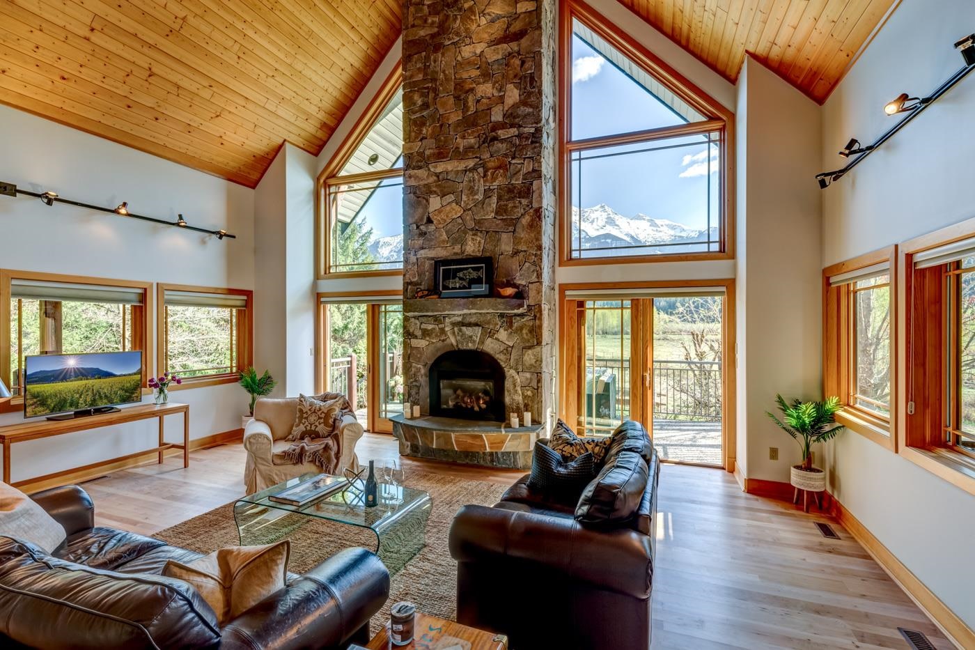 Wooden panelling on cieling with stone fireplace.