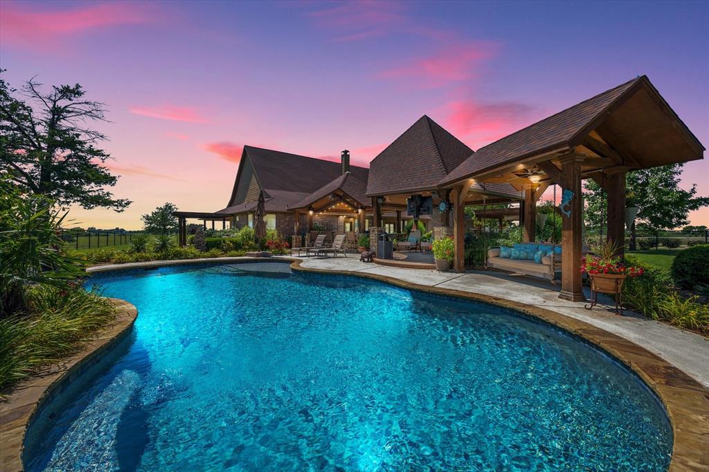 Luxury home with circular pool and sunset backdrop.