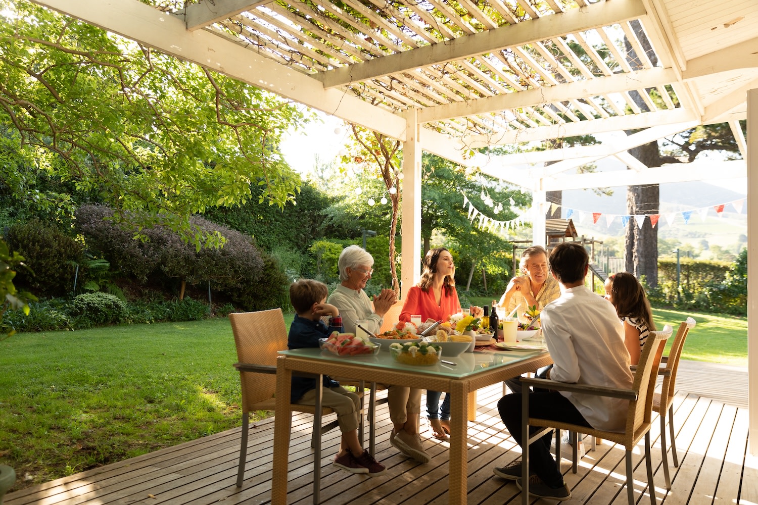 Big family, eating and lunch with food outdoor on patio with conversation, bonding or healthy meal in summer. Parents, grandparents and kids at dining table in backyard of home with talking and happy