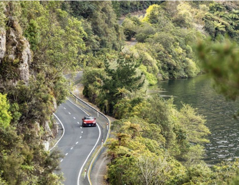 Red Ferrari Purosangue driving next to water 
