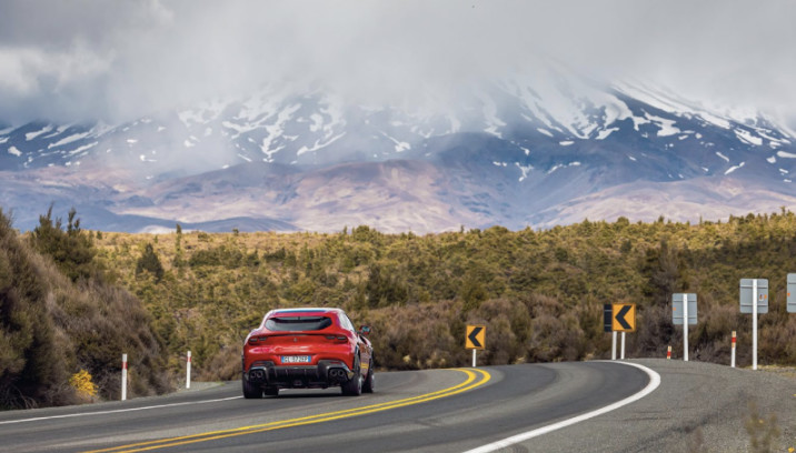 Red Ferrari Purosangue driving towards mountains 