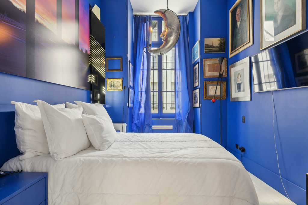 Room with white bed and cobalt blue walls.