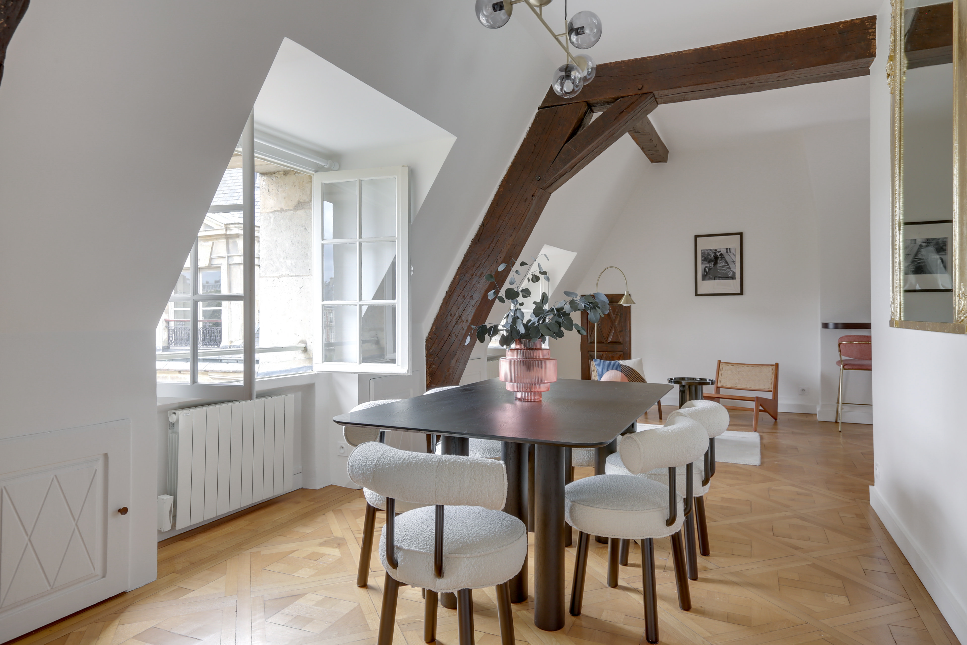 White dining room with wooden panelling and table with pink vase.