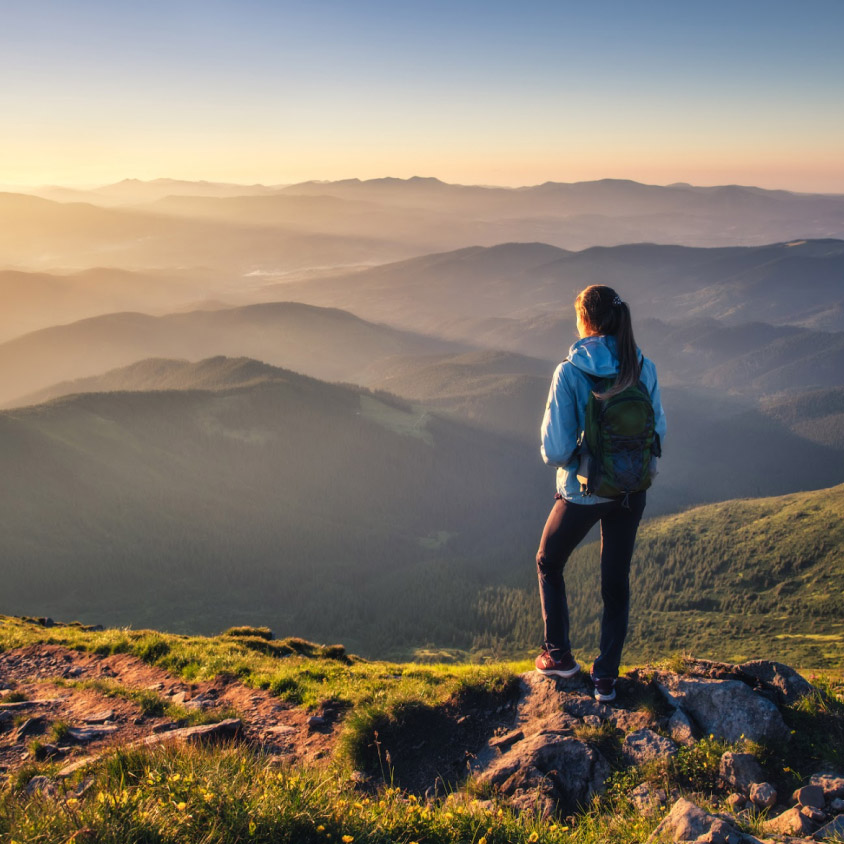 A woman looking at the horizon from the top of a hill while hiking