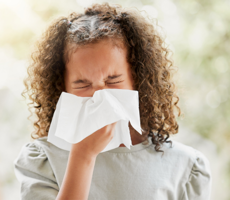 child blowing their nose with a tissue