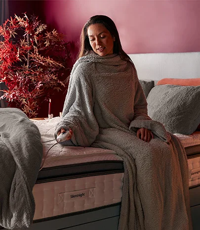 Woman wrapped up in a snugsie with fleece bedding and a warm electric blanket