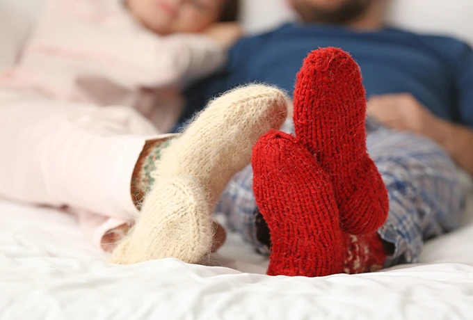 A couple lying in bed with thick fluffy socks on