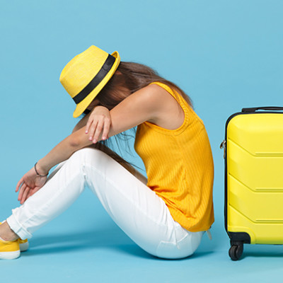 Tired woman in holiday clothes with yellow hat and suitcase