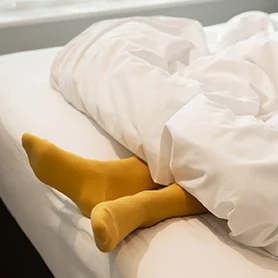 Feet wearing yellow socks sticking out from underneath a duvet 