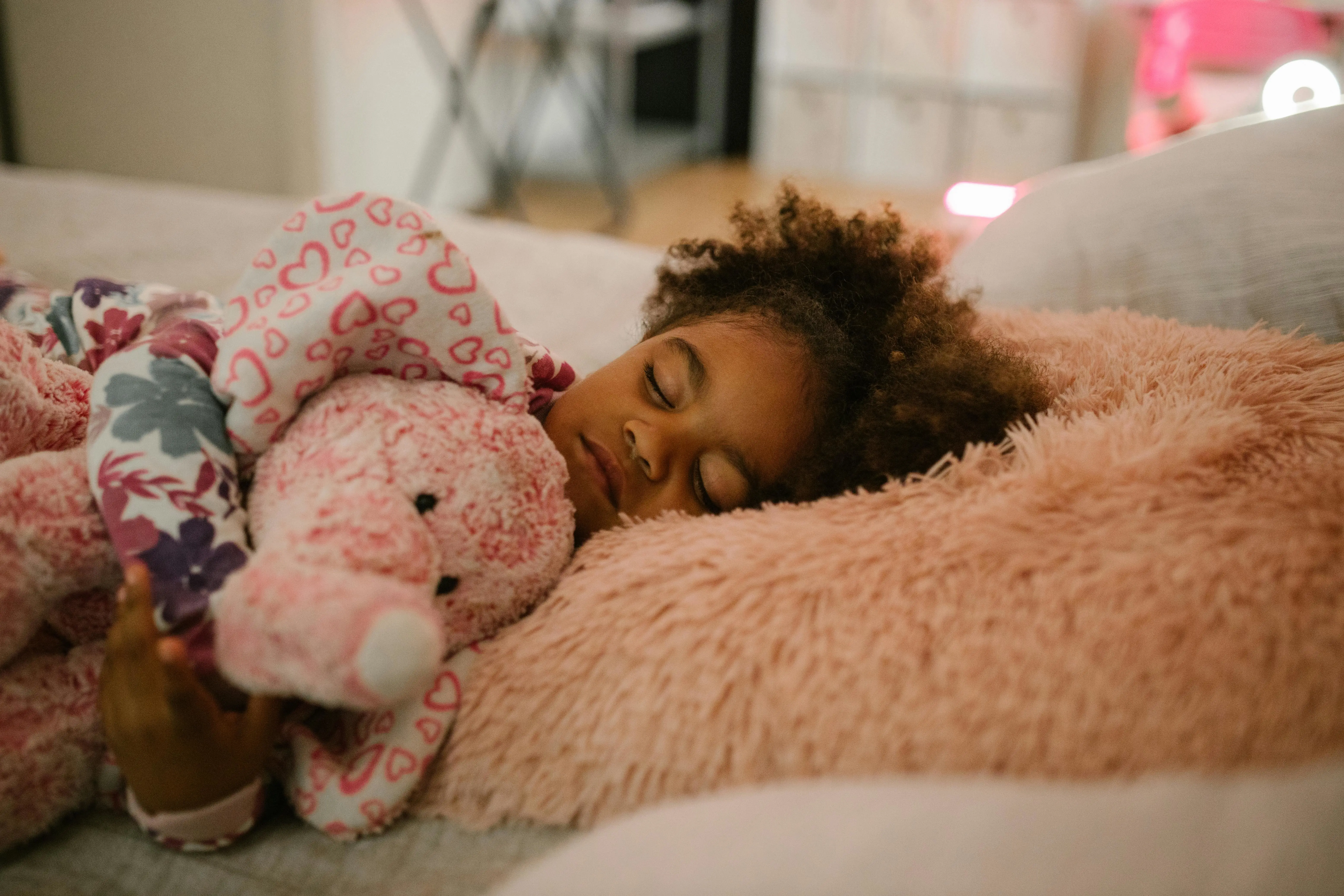 A child sleeping while cuddling a stuffed toy.