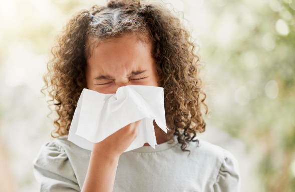 child blowing nose with tissue