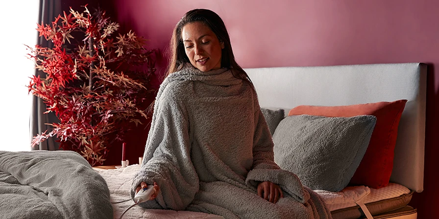Woman wrapped up in a snugsie with fleece bedding and a warm electric blanket