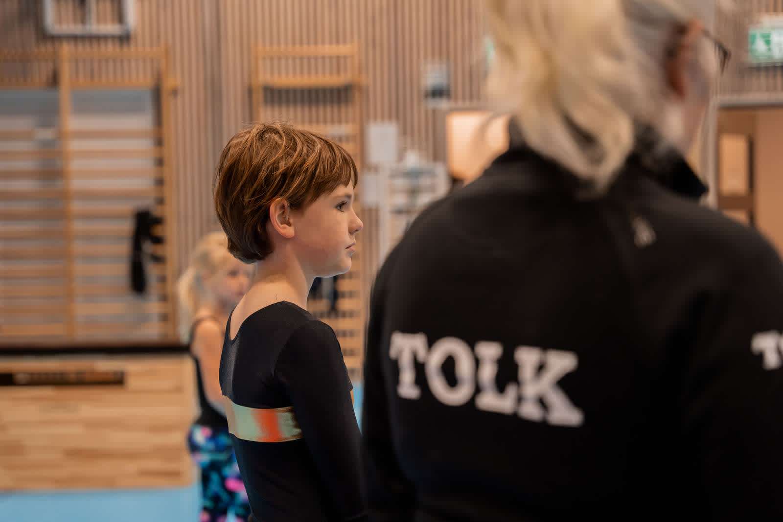 En ung gymnast med hörselnedsättning, tillsammans med en tolk