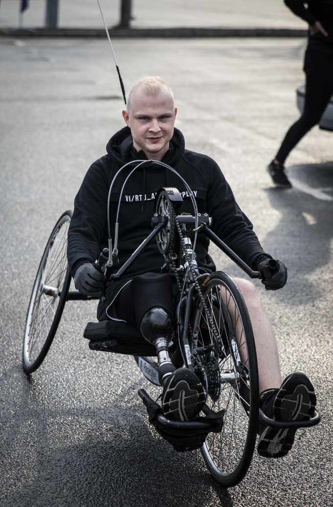 En man med ett amputerat ben cyklar med en handcykel.