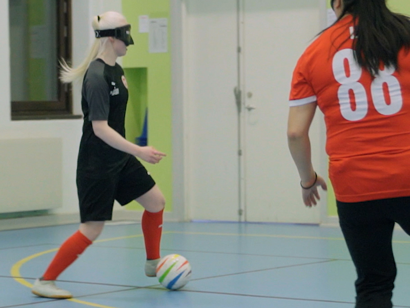 En tjej med ögonbindel dribblar med bollen.