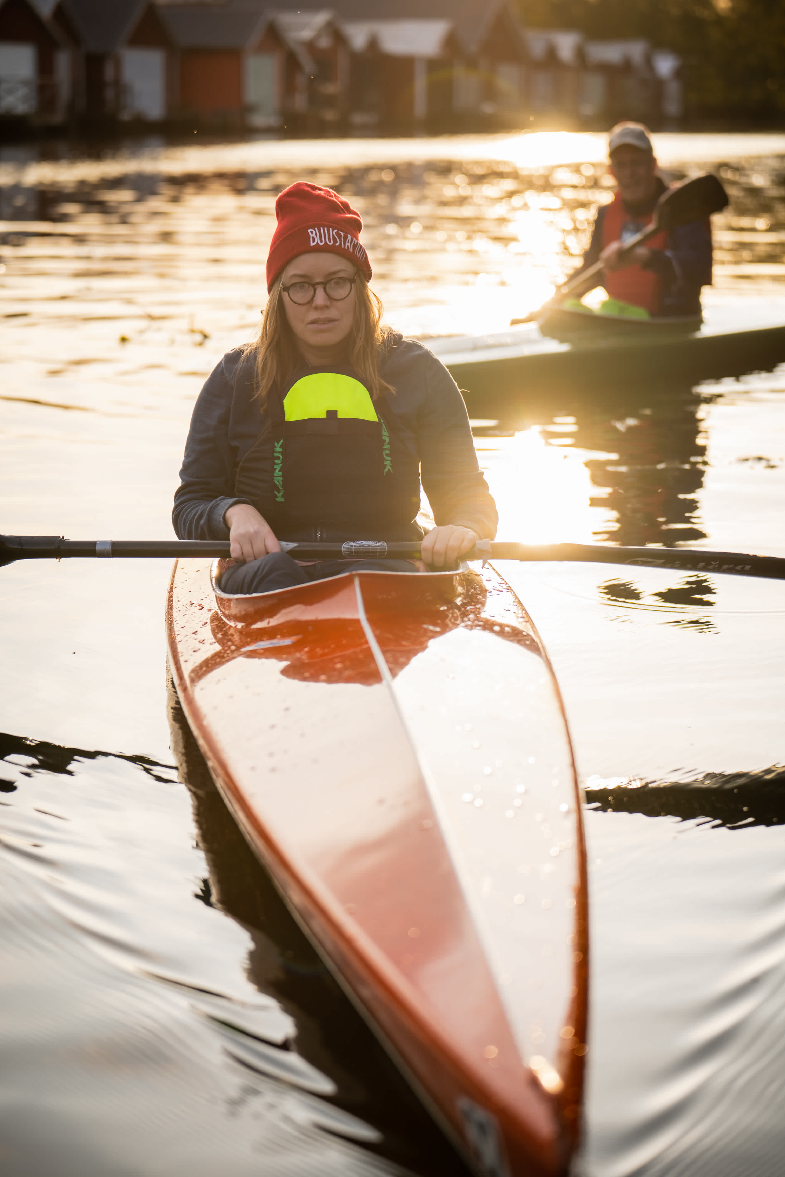 En kvinna i en kanot i solnedgången. En annan person i en annan kanot paddlar bakom henne.