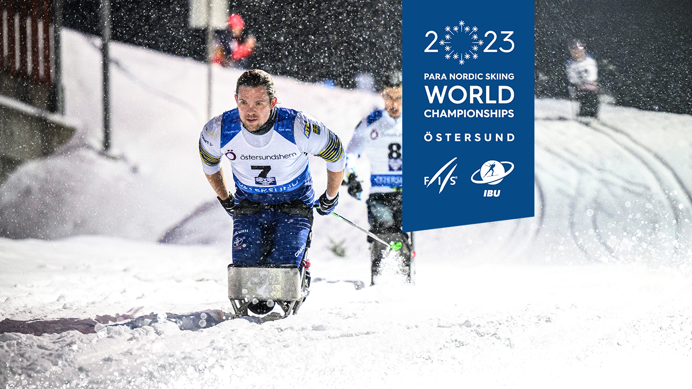 En bild på Arnt-Christian Furuberg som stakar sig fram i snön. Det är kväll och mörk himmel, banan lyses upp av strålkastare. Det snöar. VM-logotypen med texten 2023 Para Nordic Skiing World Championships Östersund.
