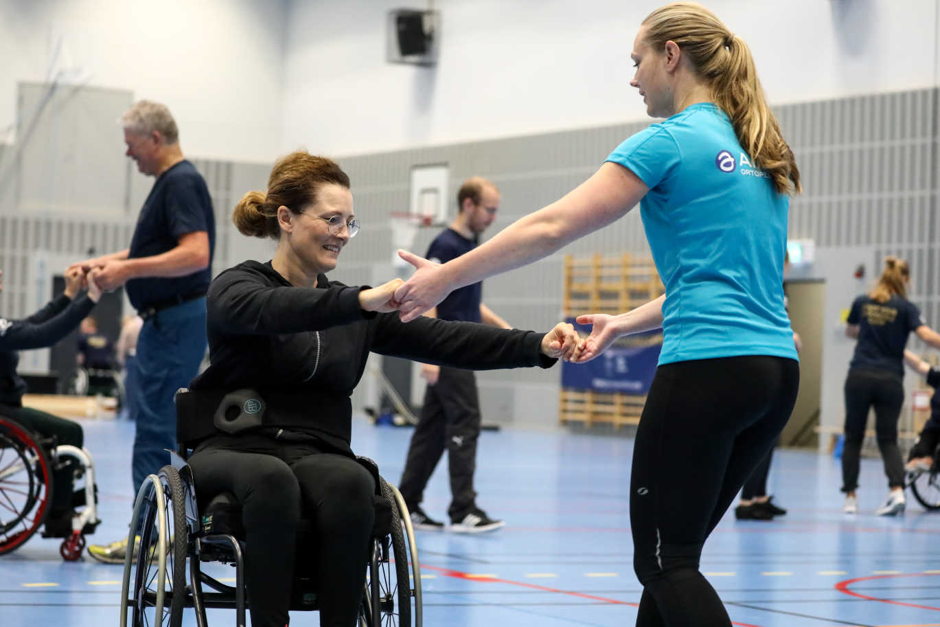 En kvinna i rullstol dansar med en kvinna utan rullstol.