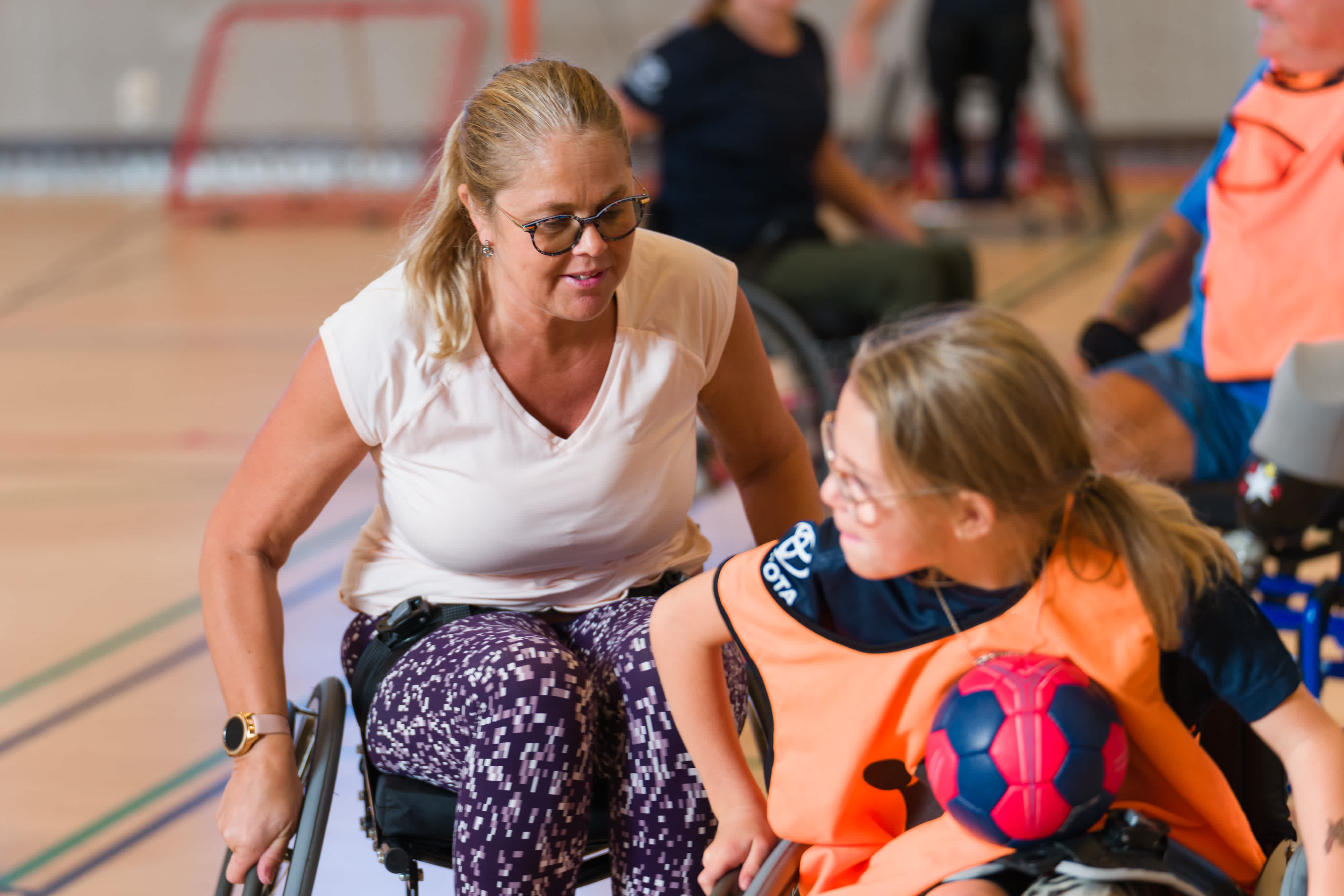 Flicka har handbollen i knät och försöker köra ifrån en motspelare som kommer bakom. 