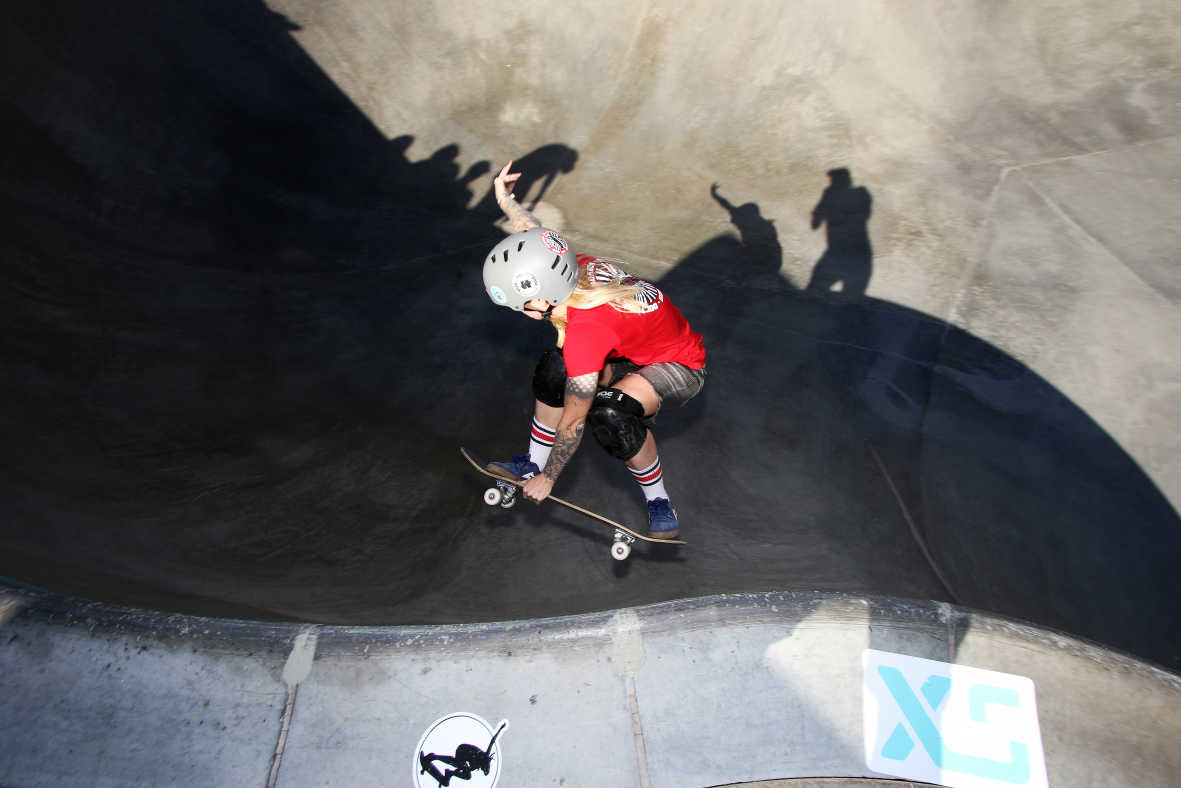 En tjej gör ett trick mot kanten i en skateboardpark.
