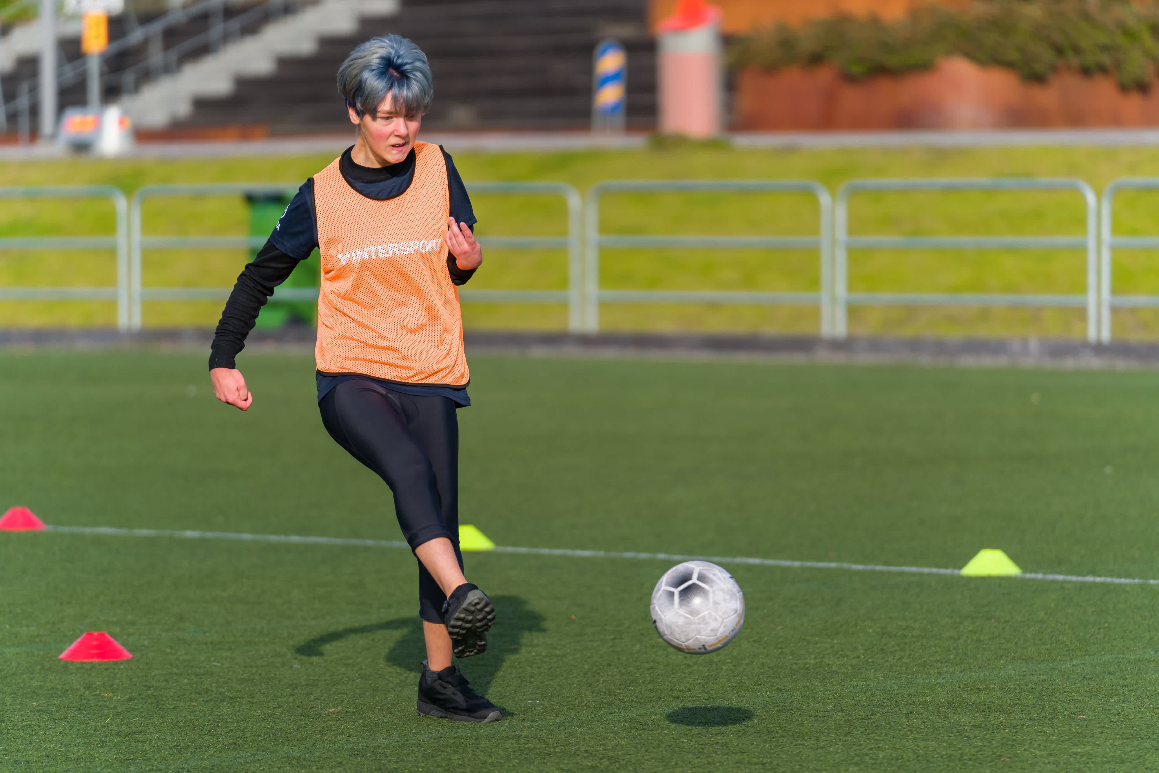 Ung kvinna på fotbollsplanen har precis skjutit iväg bollen.