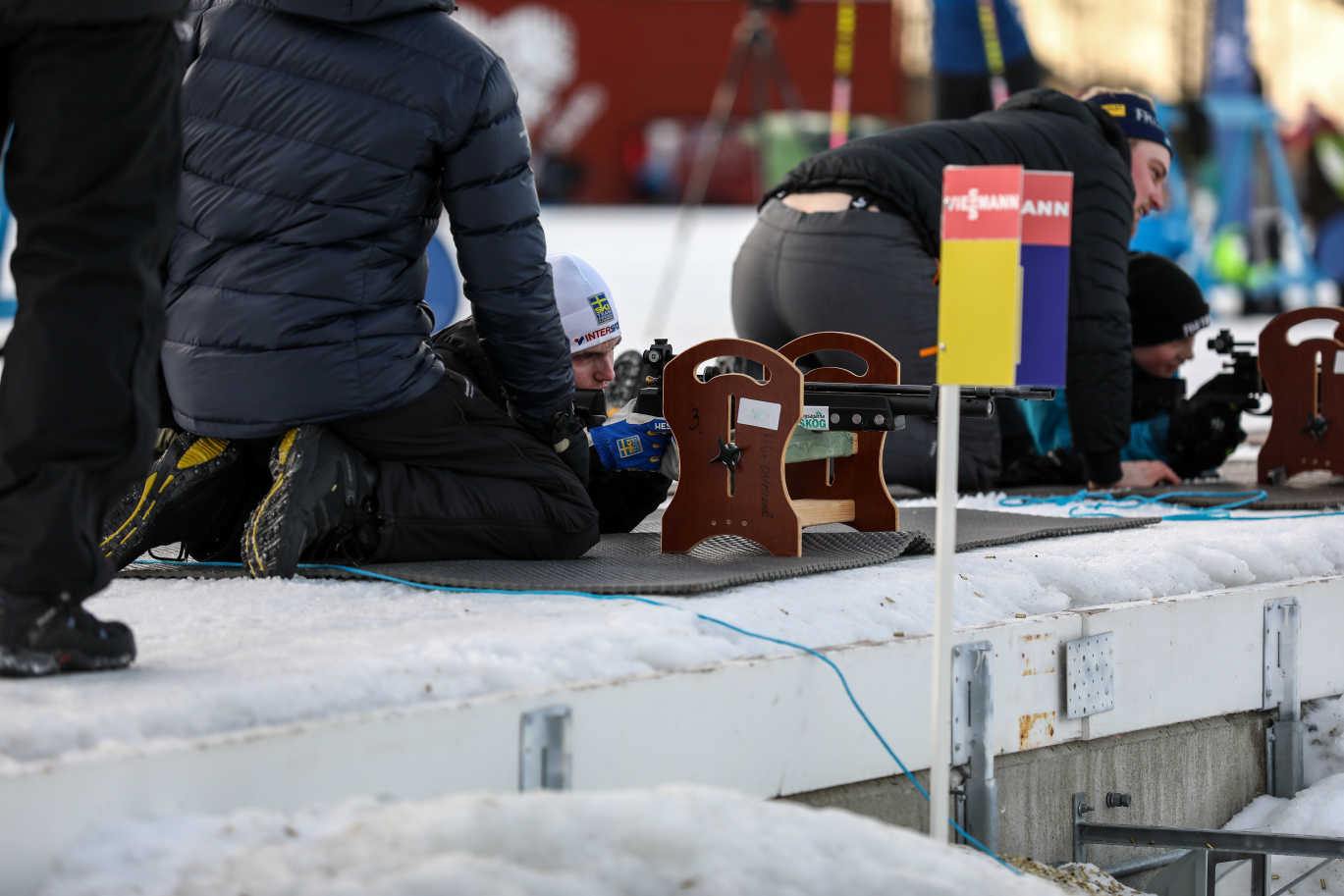 Två pojkar ligger på mage bredvid varandra och siktar med luftgevär. De har hjälp av varsin ledare.