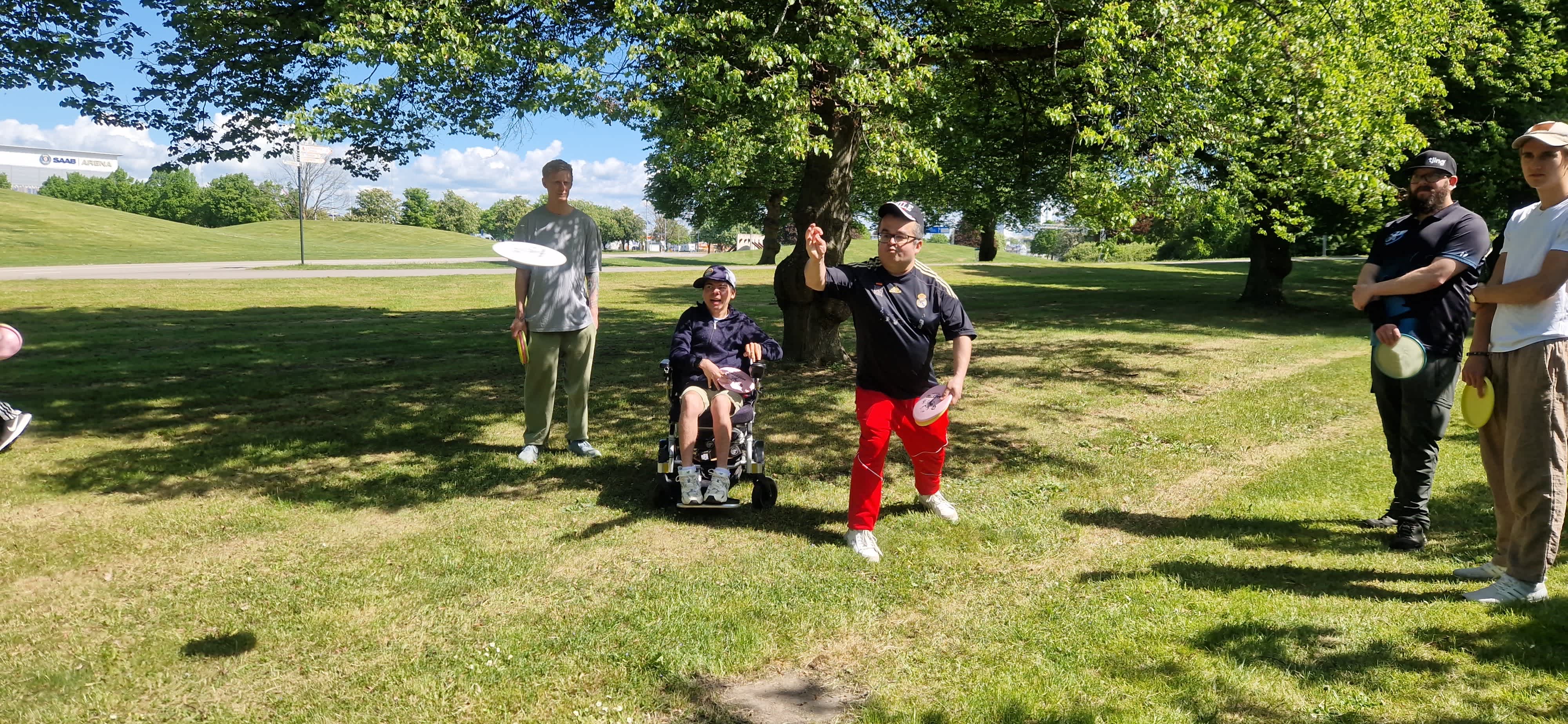 En person kastar en frisbee mot en korg.