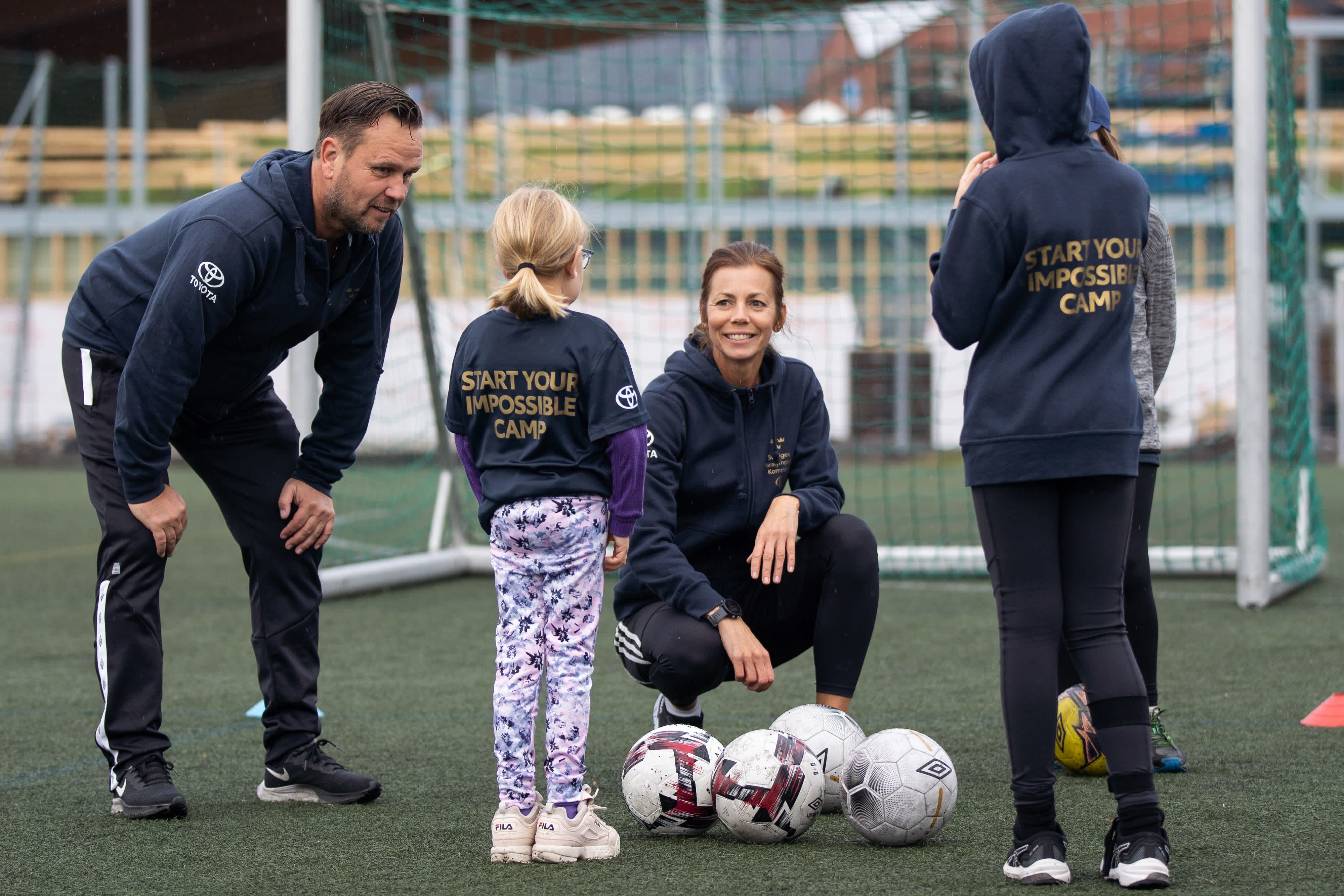 Ledare och deltagare på fotbollspasset samlas framför ett mål på fotbollsplanen. 