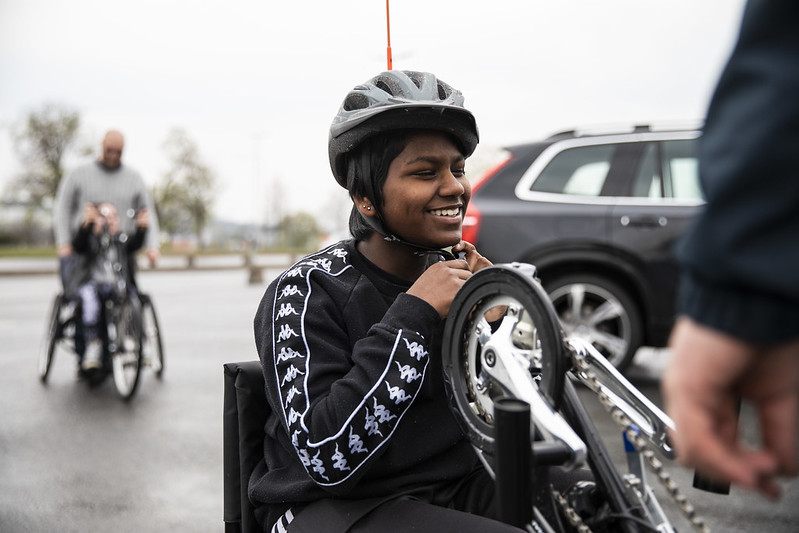 Mala ler och knäpper på sig hjälmen innan hon tar en tur på handcykeln.