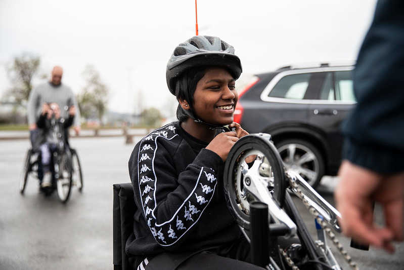 Mala ler och knäpper på sig hjälmen innan hon tar en tur på handcykeln.