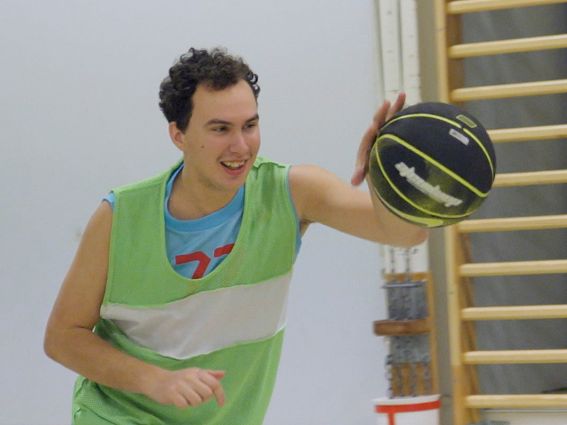 En kille ler och studsar bollen.