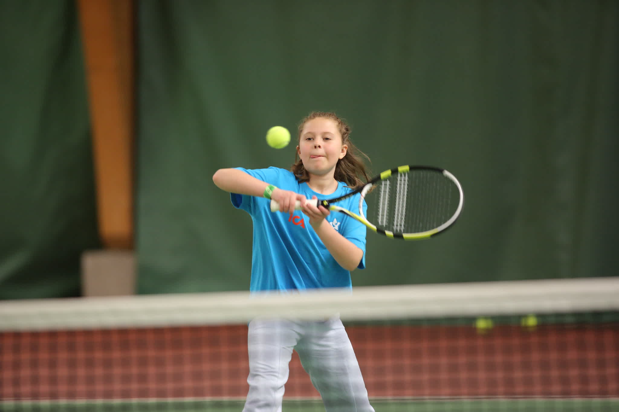 En tjej ska precis slå iväg en tennisboll över nätet