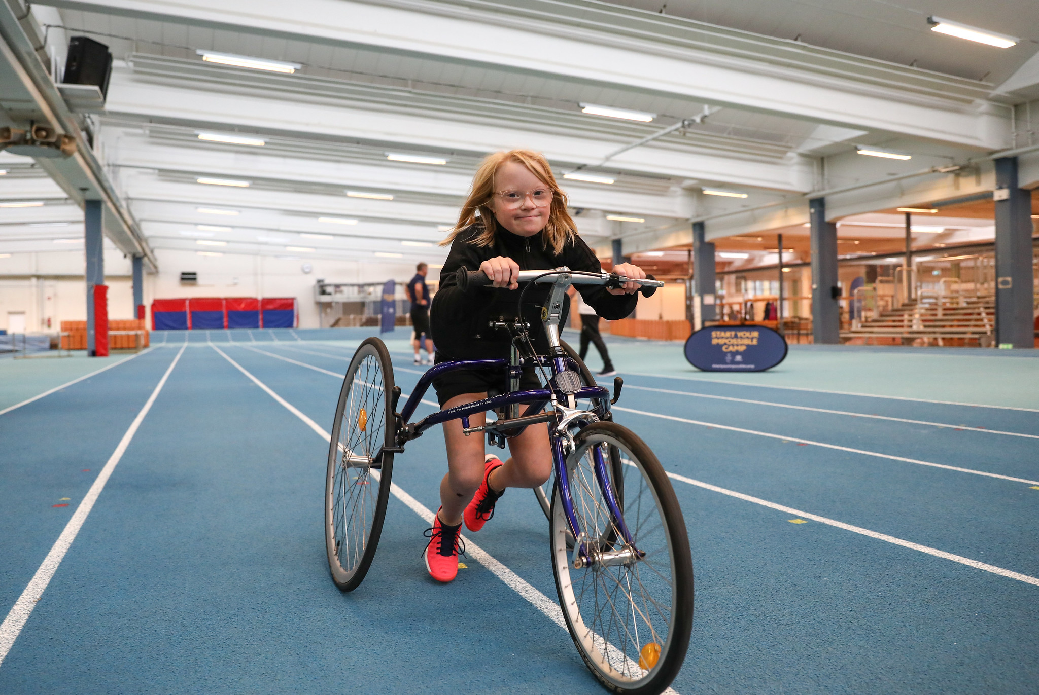 En ung tjej sitter på sin cykel på en framerunningbana.