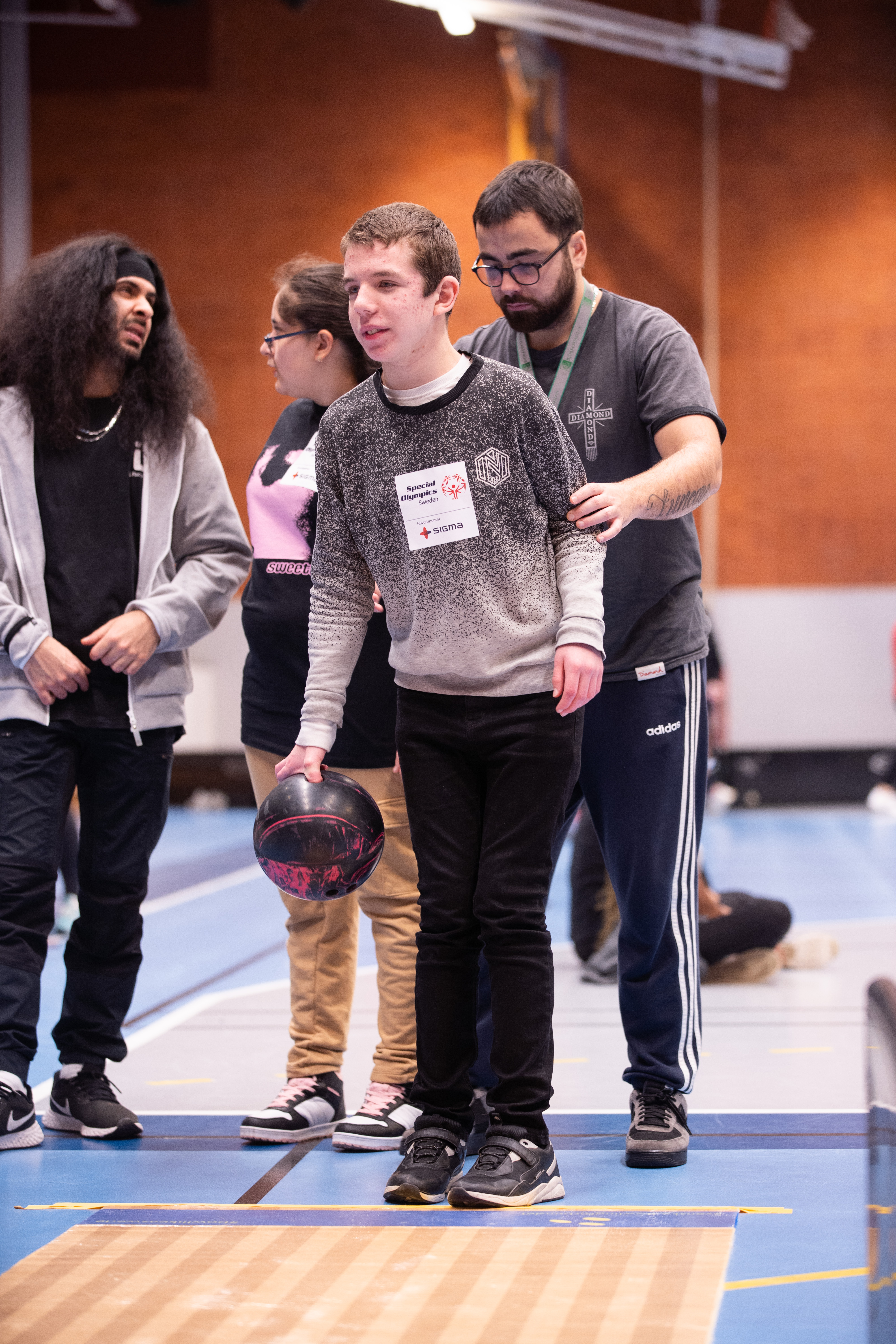 Kille med synnedsättning får hjälp av assistent att sikta in sitt kast.